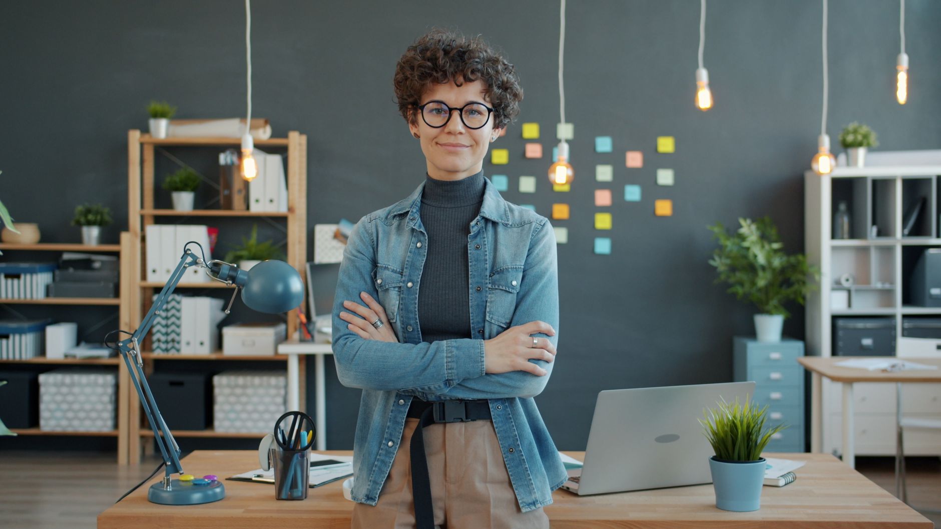 Confident employee standing in a modern office, showcasing creativity and professionalism.